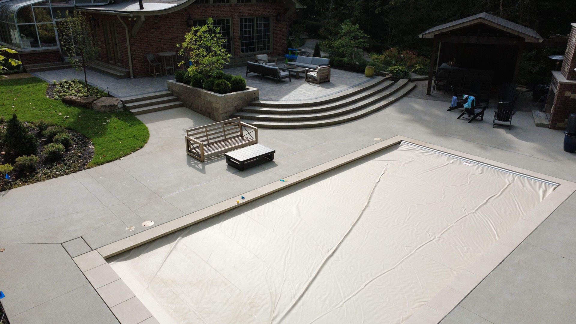 Beautiful modern residential pool deck and surrounding patio in stamped concrete — clean minimalist landscaping, soft morning light, premium custom home setting in Indianapolis with decorative coping and walkways